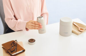 テーブルで水筒を持つ女性