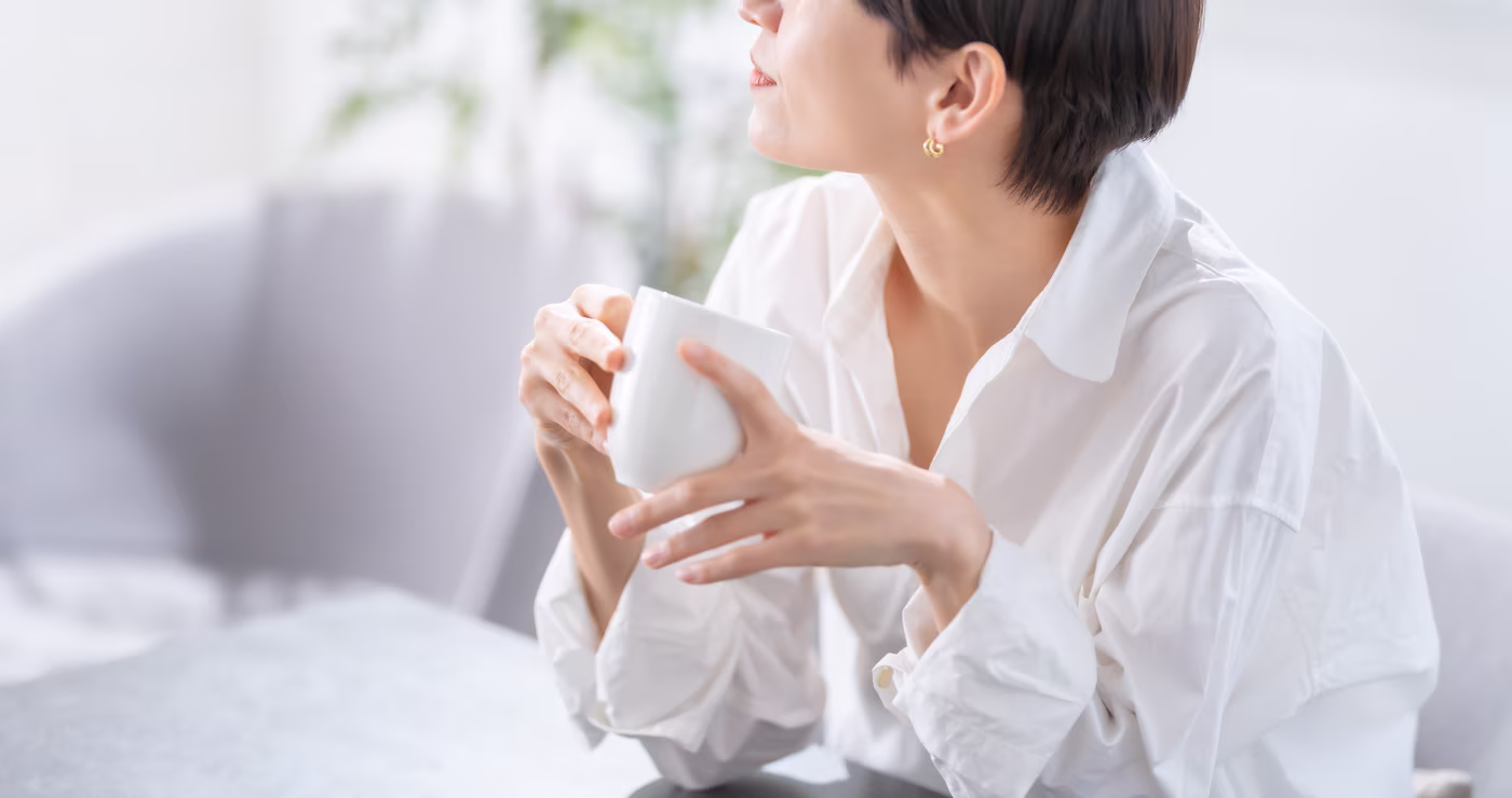 A relaxed woman sitting comfortably on a chair, peacefully enjoying her morning drink.