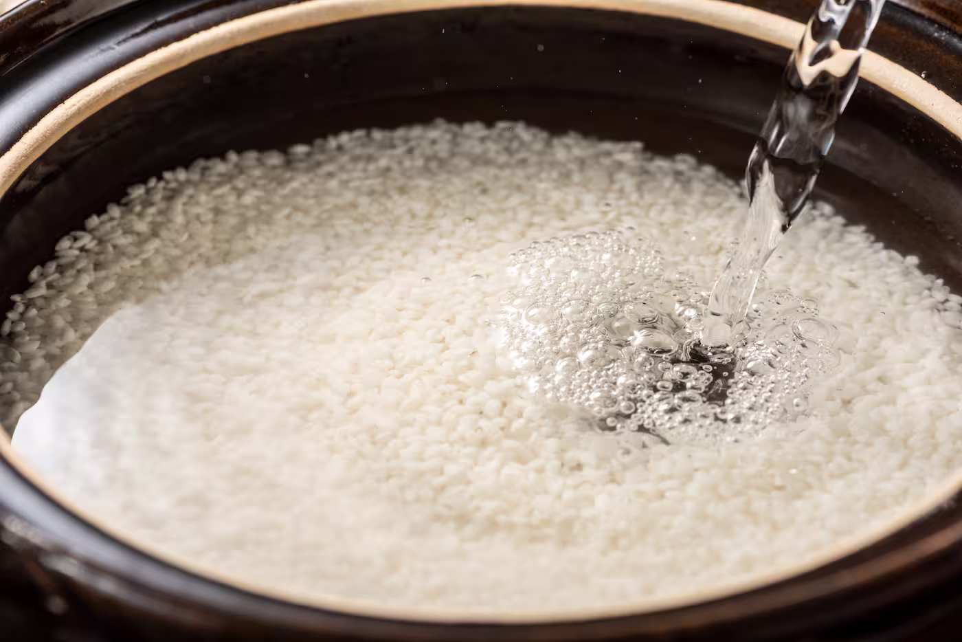 お米が入った土鍋に水を注いでいる様子