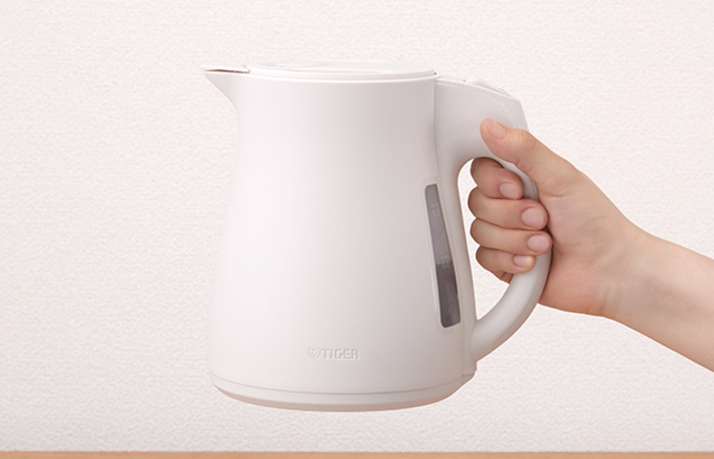 A person holding a clean electric kettle by its handle.