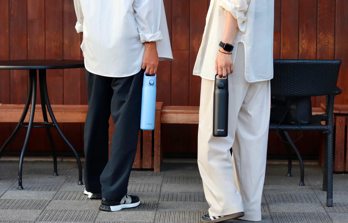 Two people standing together holding water bottles.